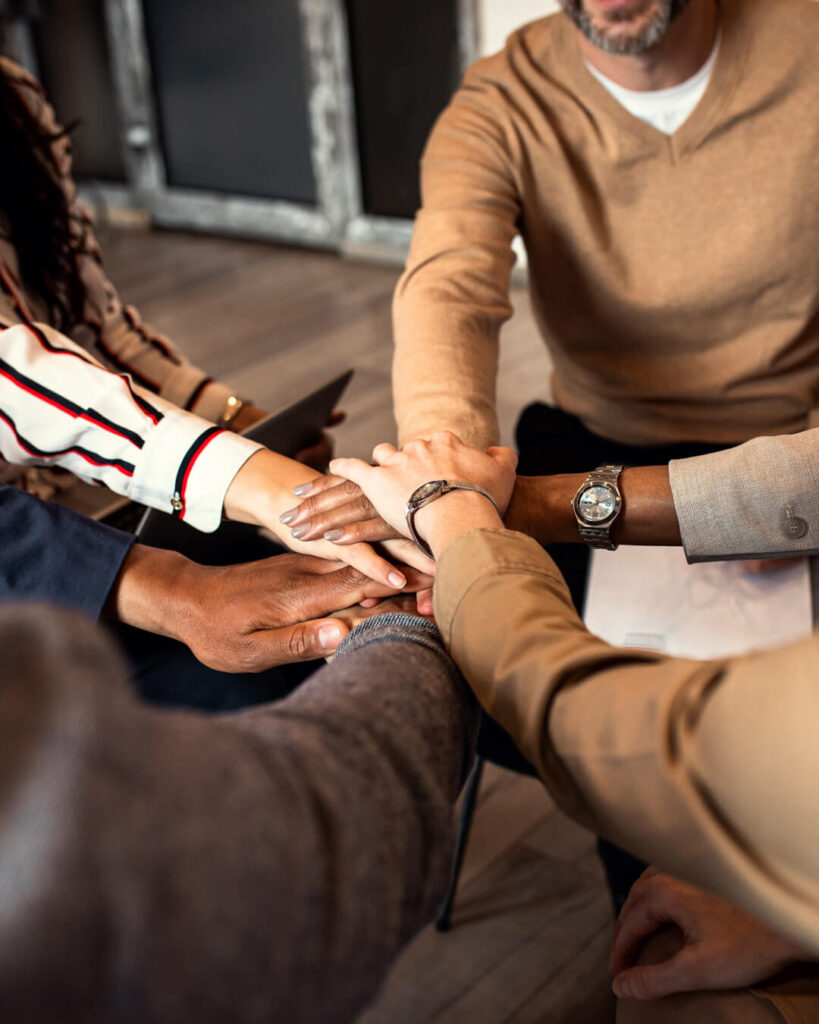 Top-Management Coaching bei BY BEING YOU: Führungsteam legt die Hände aufeinander, wieder eine Einheit